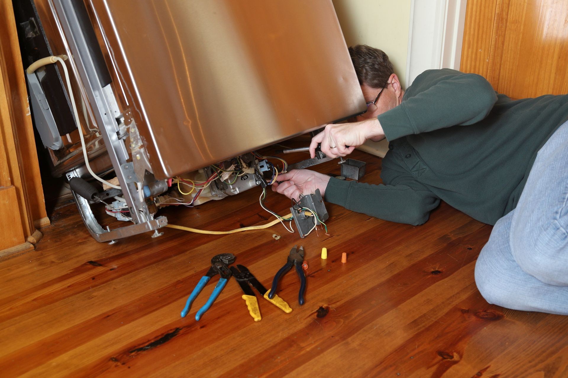 Maintenance technician repairs borken dishwasher appliance in a house